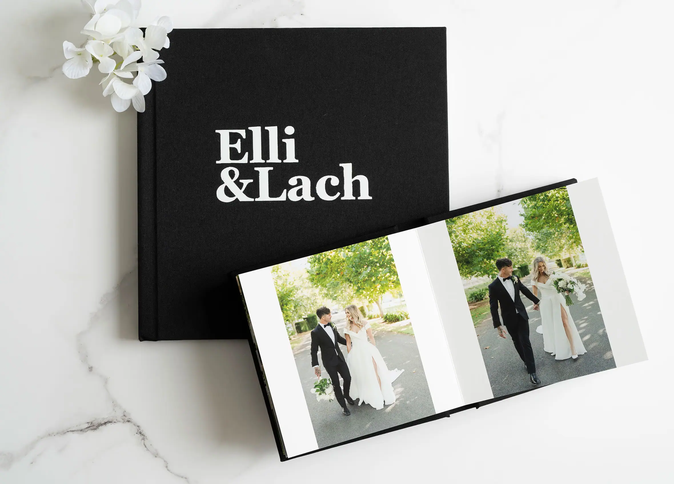 Black wedding album and an open album displaying portraits of a couple.