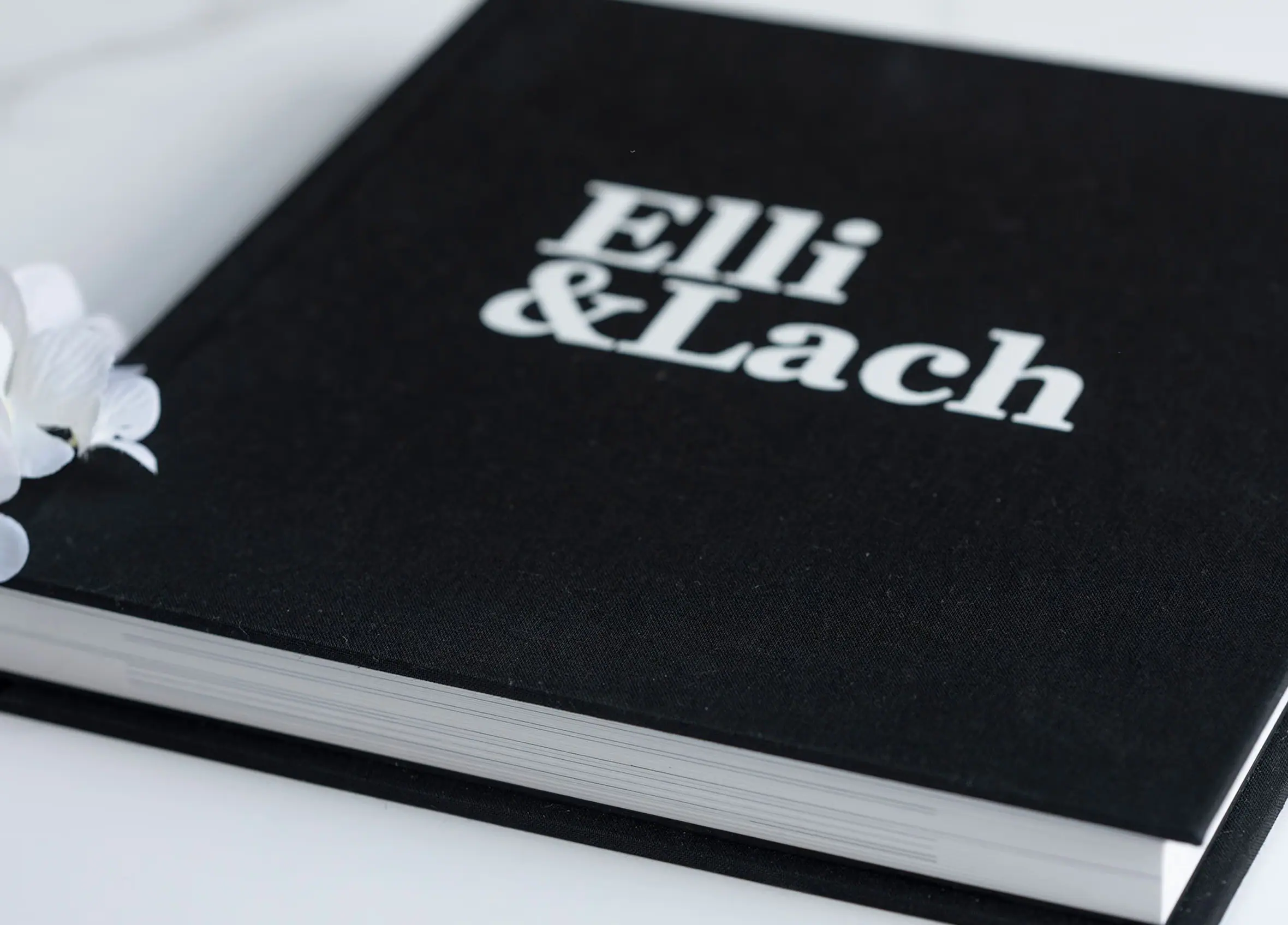 Close-up of a black wedding album cover with white lettering.