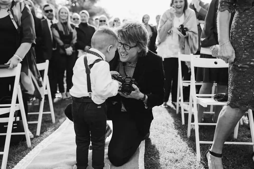 Black-and-white photograph of a woman crouching to greet a small boy at a ceremony.