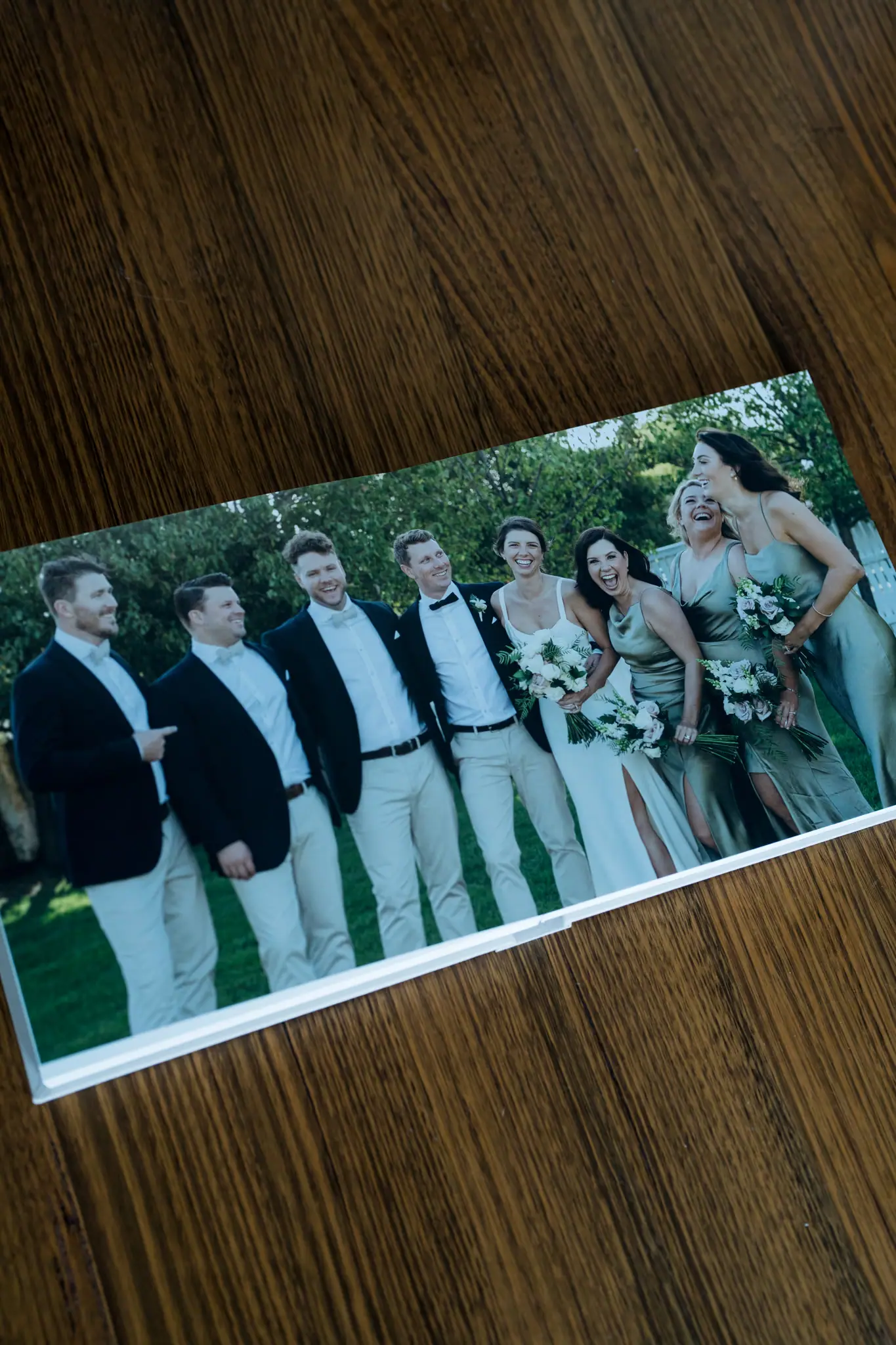 Printed wedding party photograph resting on a wooden table.