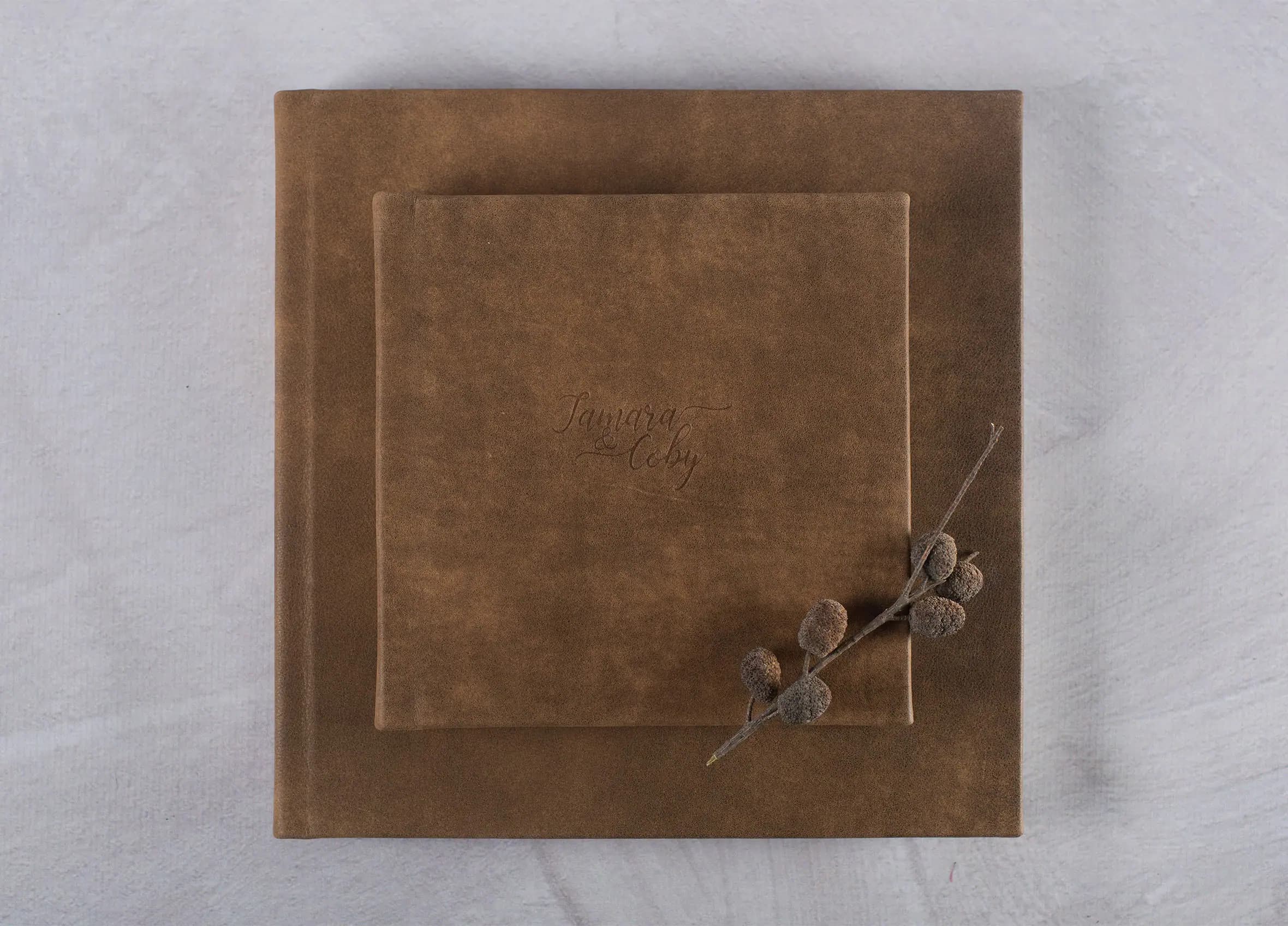 Brown leather wedding album cover with a sprig of leaves.