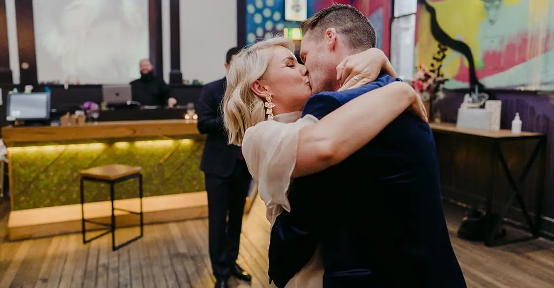 Two grooms embracing in a colourful reception room