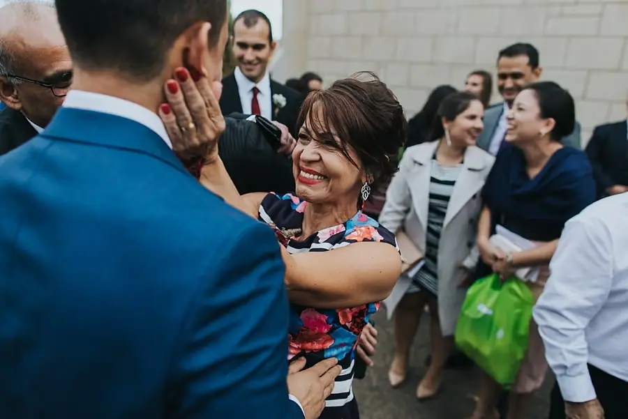 Woman smiling and reaching toward a man among guests outside.