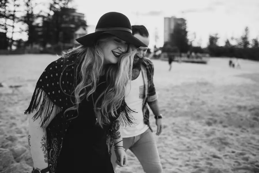 Black-and-white photograph of a woman smiling beneath a wide-brimmed hat beside her partner.
