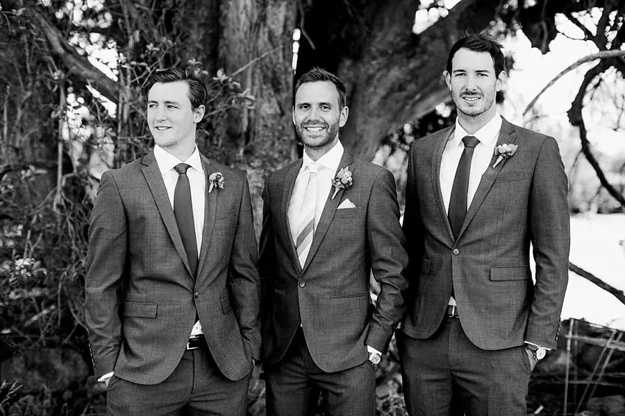 Black and white photograph of three suited men posing beneath a tree.