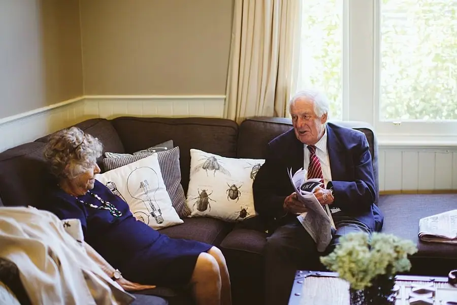 Older guests sit and chat on a sofa.