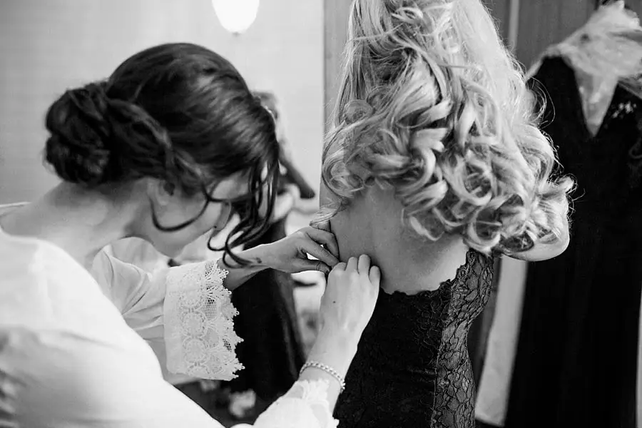 Black and white close view of the bride and a friend helping with her dress.
