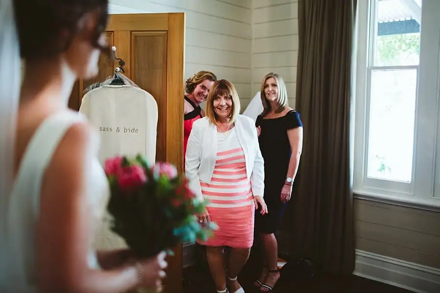Guests smile toward the bride beside a hanging garment bag.