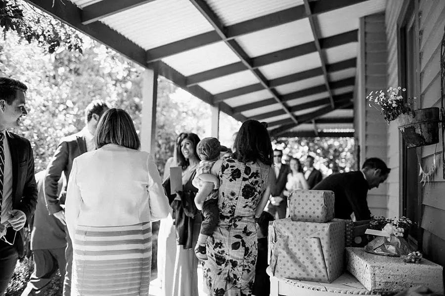 Black and white photograph of guests chatting on the veranda.