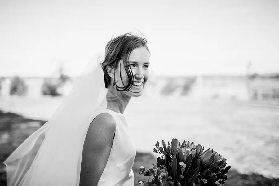 Black and white portrait of the bride smiling with her bouquet.