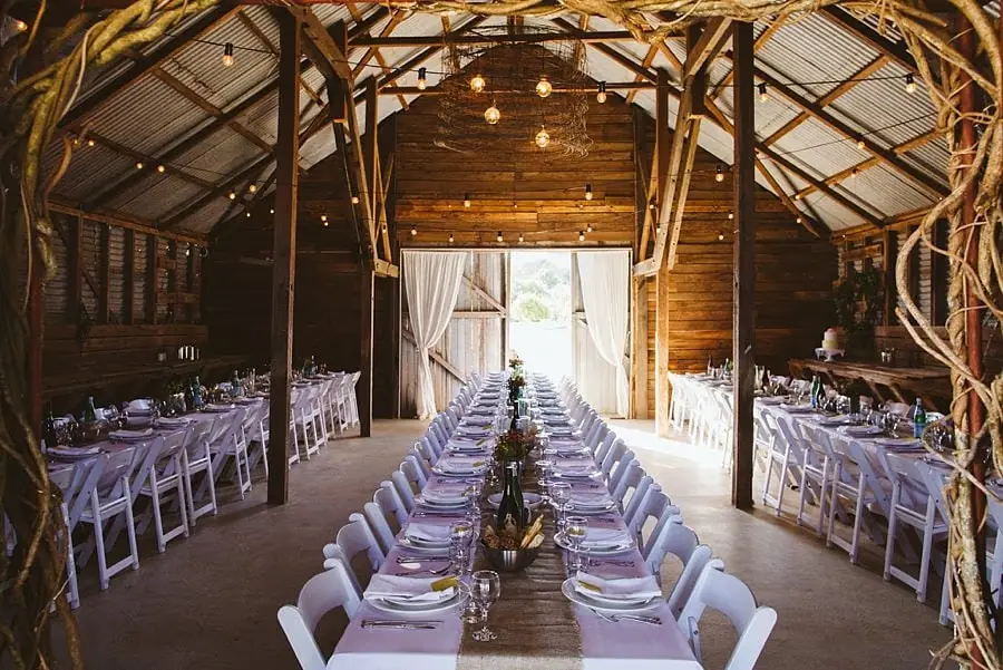 Long reception tables beneath exposed timber rafters and hanging lights.