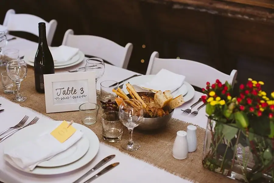 Table setting with flowers, bread, wine and a table-number card.