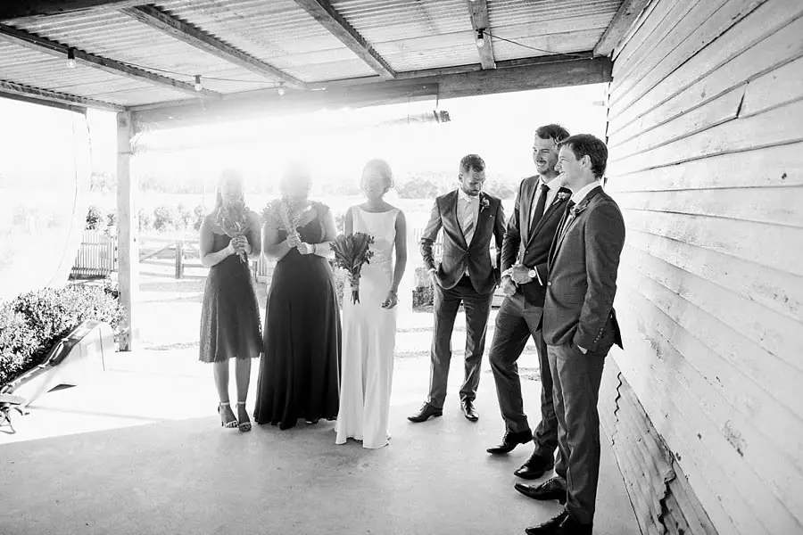 Black and white photograph of the wedding party standing in the barn doorway.