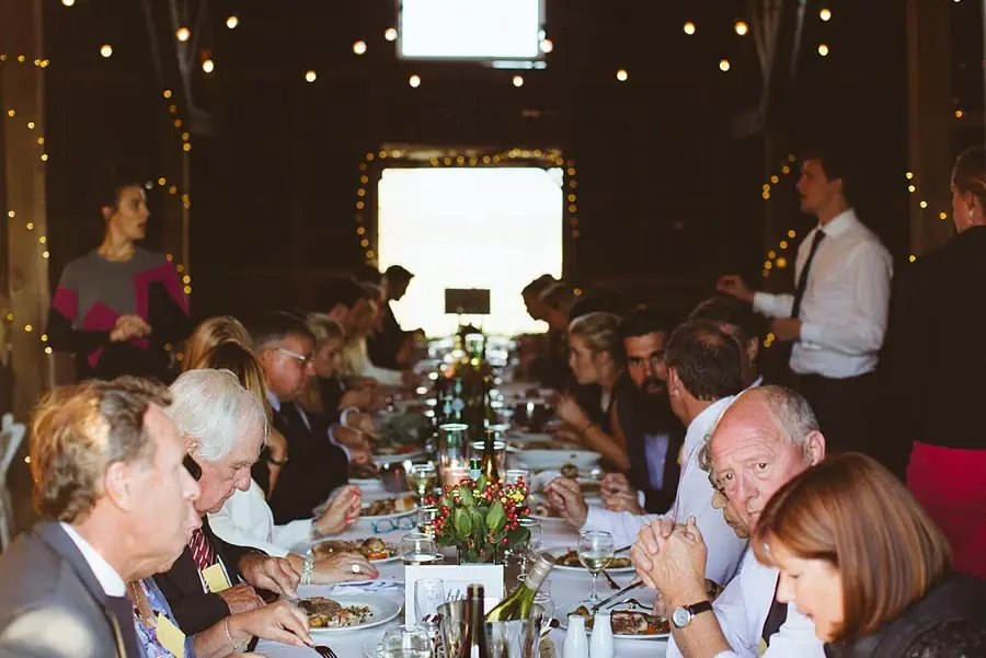 Guests eat together at a long table beneath reception lights.