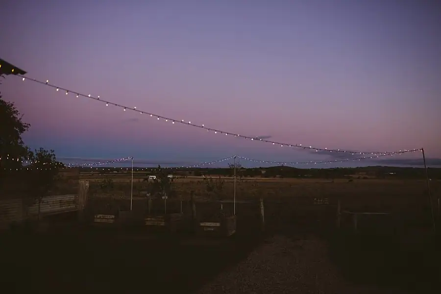 Outdoor string lights beneath a purple evening sky.