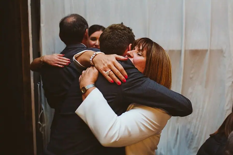 Guests embrace together beside the reception curtains.