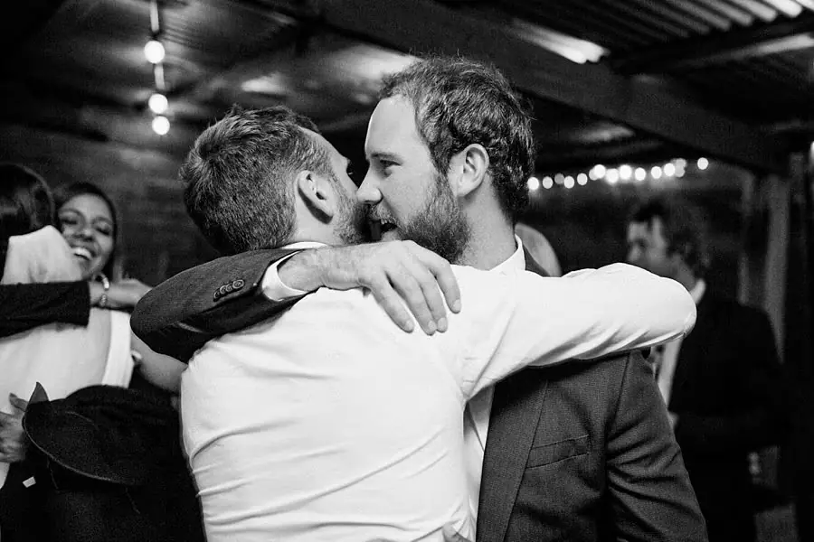 Black and white photograph of two men embracing at the reception.