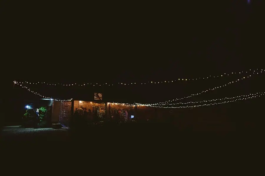 Reception building illuminated beneath long strands of outdoor lights at night.