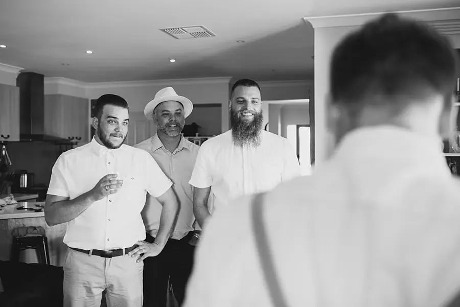 Black-and-white photograph of men laughing together in a kitchen.
