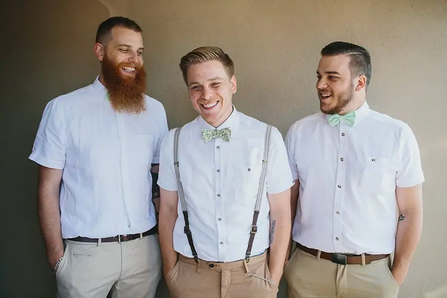 Three men smiling in white shirts and bow ties.