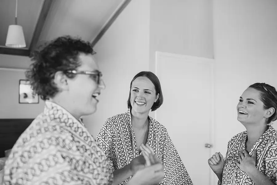 Black-and-white photograph of three women laughing in patterned robes.