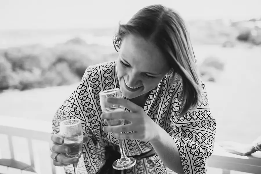 Black-and-white photograph of a woman smiling over a raised glass.