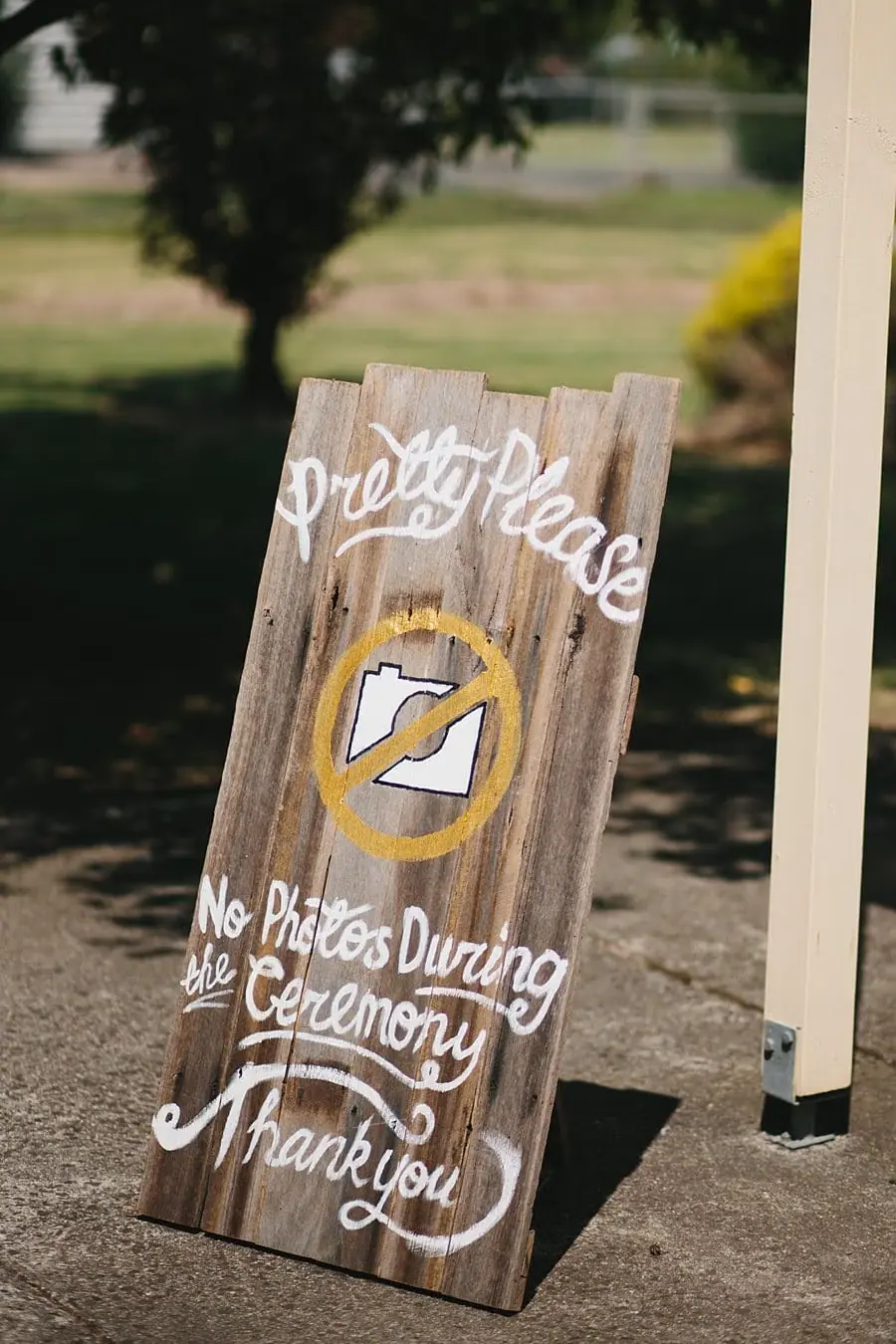 Wooden sign requesting no photographs during the wedding ceremony.