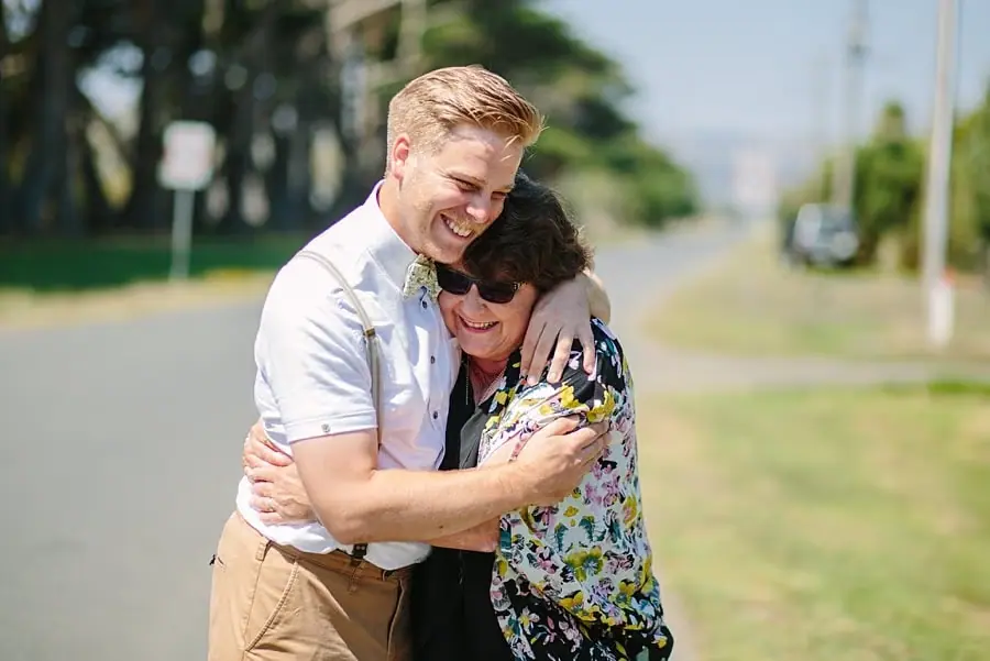 Groom embracing a woman outdoors beside a road.