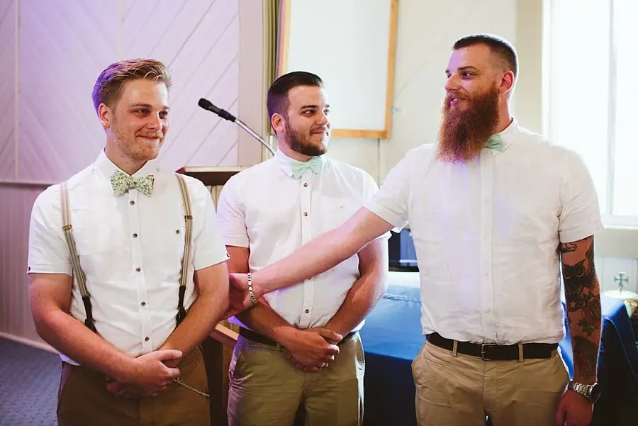 Groom and two companions standing at the front of the church.