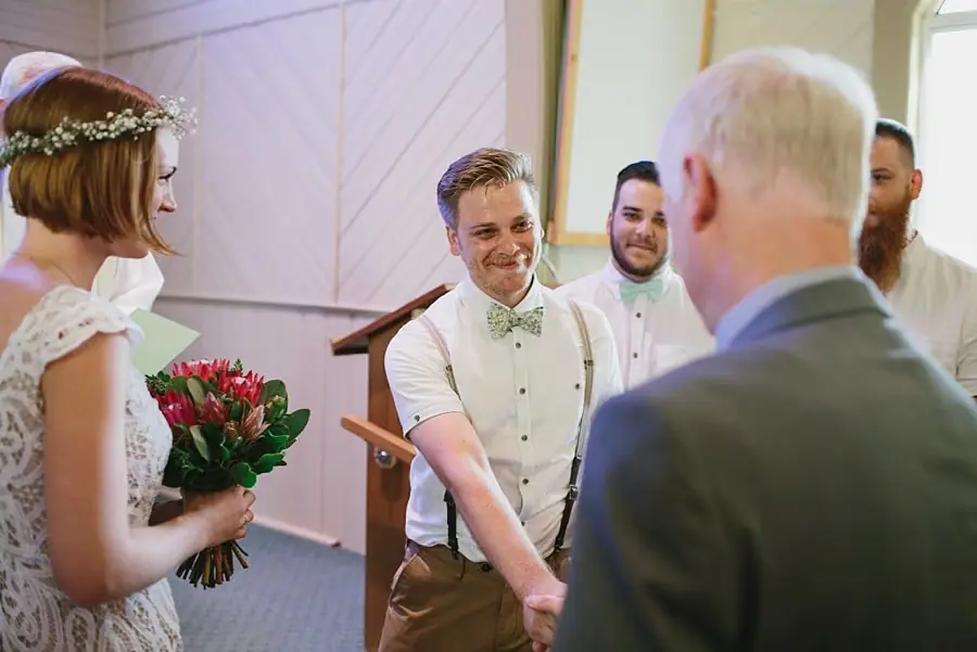 Groom smiling toward the bride while standing inside the church.