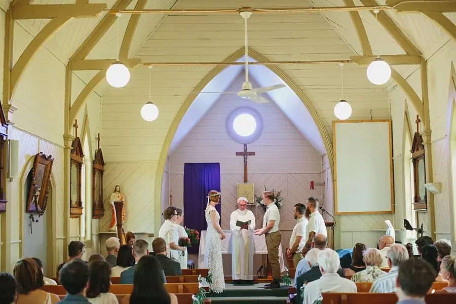 Wide view of the couple and officiant at the front of a small church.