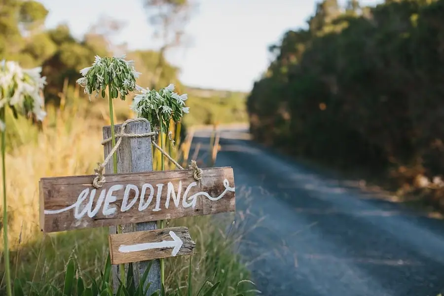 Wooden wedding direction sign beside a rural driveway.