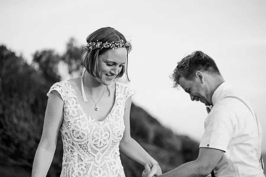 Black-and-white photograph of the couple looking down while holding hands.