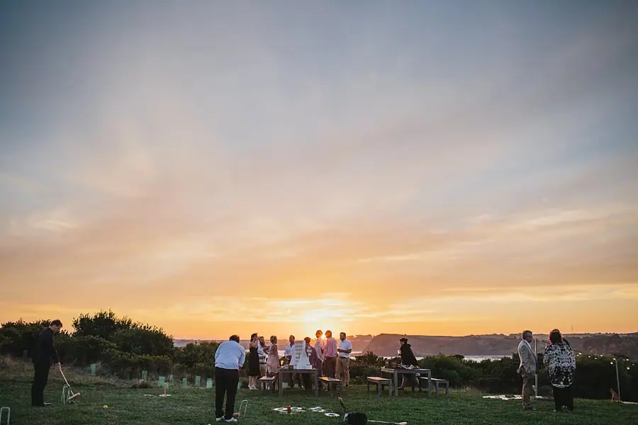 Guests gathered on a lawn beneath a colorful sunset sky.