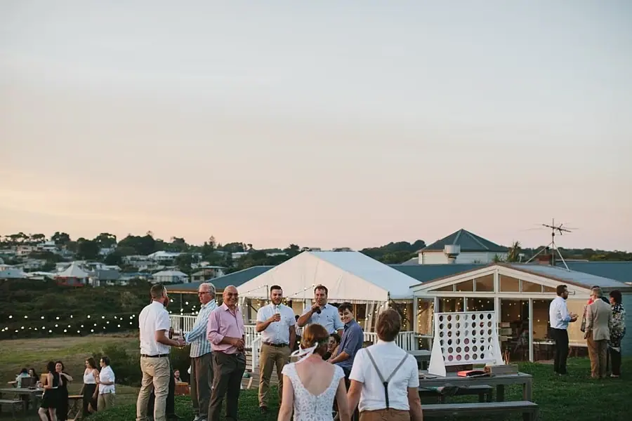 Guests chatting outside a house with a veranda and reception marquee.
