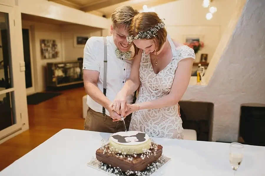 Bride and groom cutting a round wedding cake together.