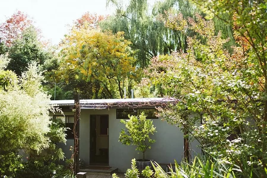 Small garden building surrounded by leafy trees.