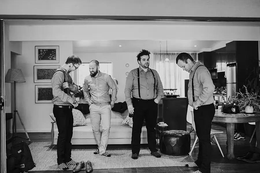 Black and white photograph of men getting ready together in a living room.