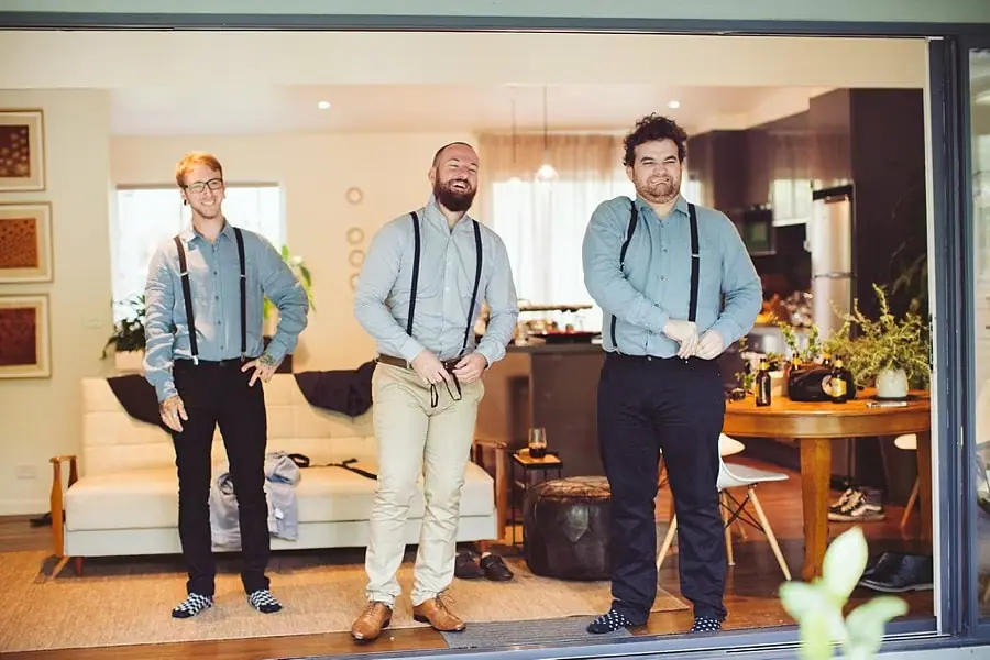 Men in shirts and braces stand together indoors.
