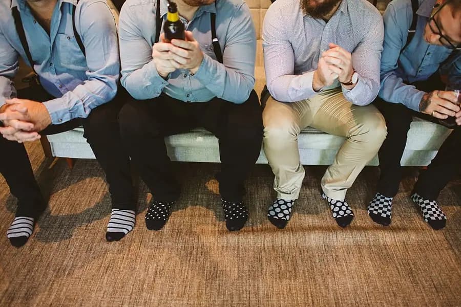 Seated men show patterned socks while holding drinks.