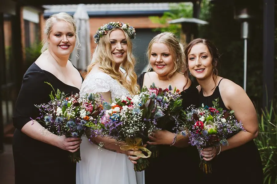 Bride and three bridesmaids pose together holding bouquets.