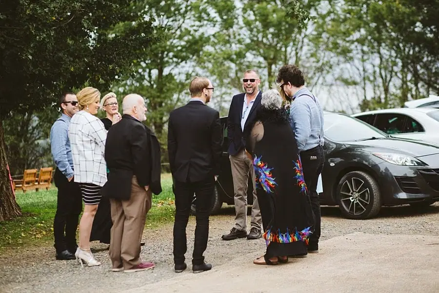 Guests chat beside parked cars before the ceremony.