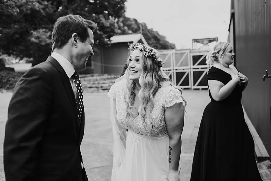 Black and white photograph of the bride greeting a suited man outdoors.