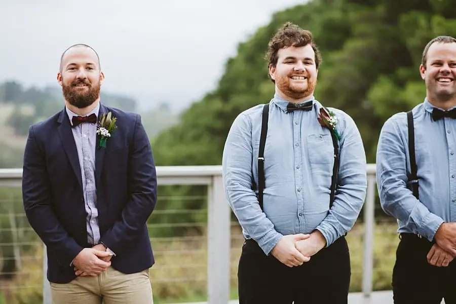Groom and groomsmen smile while waiting at the ceremony.