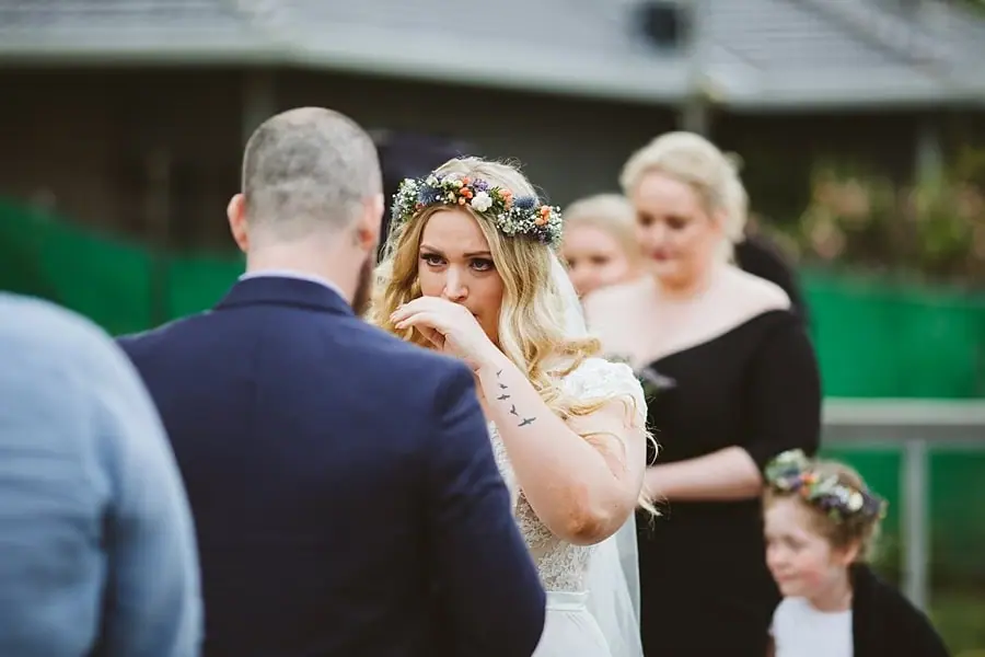 Bride wipes her eye while facing the groom.