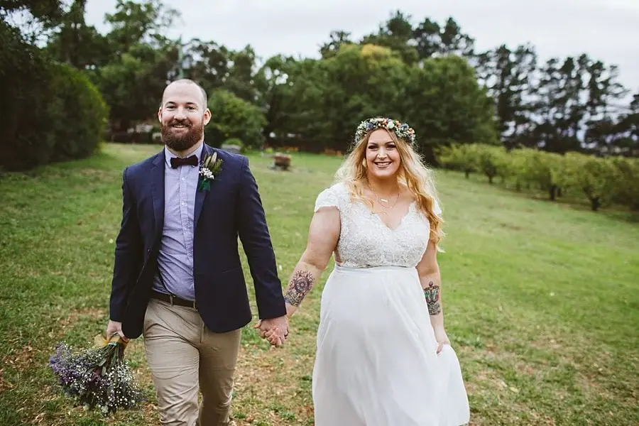 Bride and groom smiling as they walk together across the grass.