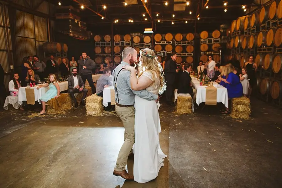 Bride and groom dancing together while reception guests watch.