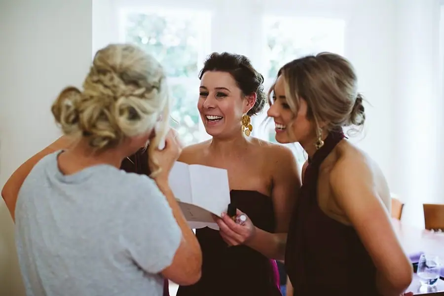 Women laughing together while one holds a folded note.