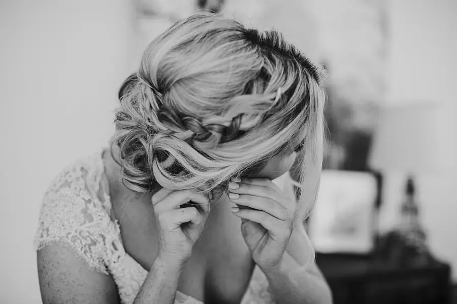 Black-and-white portrait of the bride fastening an earring.