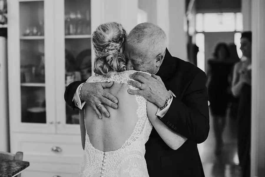 Black-and-white photograph of the bride embracing a man in a dark suit.